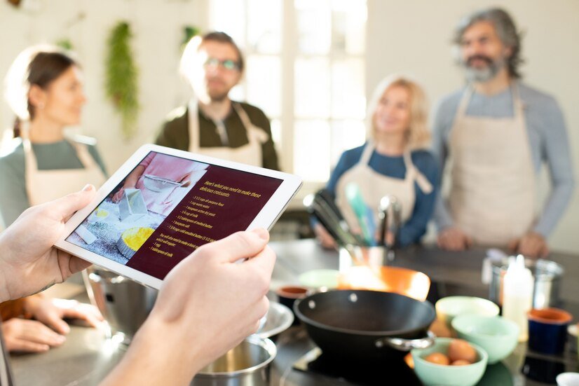 hands-male-cooking-coach-with-tablet-looking-through-online-recipe-delicious-homemade-croissants-against-group-his-trainees_274679-26253